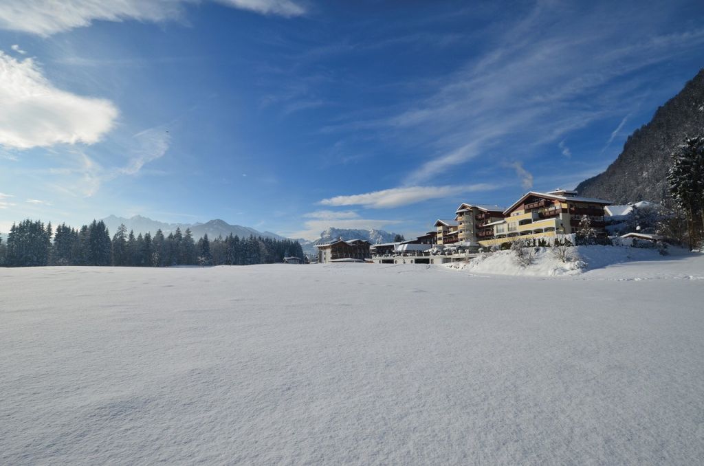 Aussenansicht auf das winterlich eingeschneite Hotel (Alpina Kössen)
