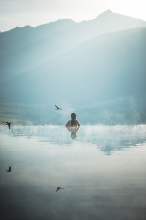 Frau im Sky Pool mit traumhaftem Ausblick (Alpin Panorama Hotel Hubertus)
