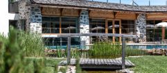 Sicht auf den Naturbadeteich und den Outdoorpool (Tirler - Dolomites Living Hotel)