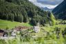 Blick auf das Naturhotel Rainer eingebettet in sommerliche Bergwiesen (Naturhotel Rainer)